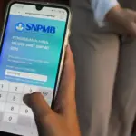 Tampilan orang memegang HP melihat hasil SNBT