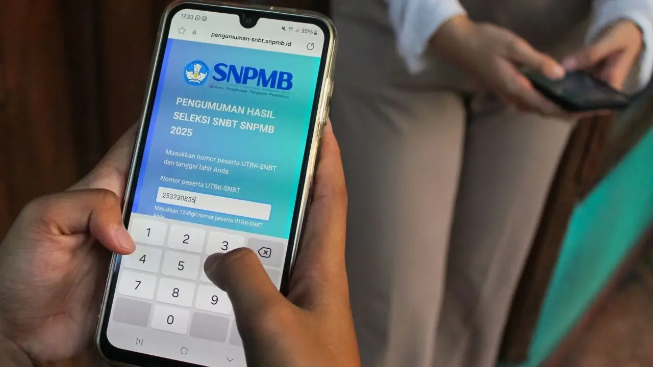 Tampilan orang memegang HP melihat hasil SNBT